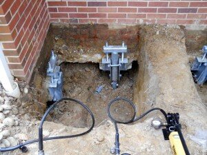 Helical piles attached to brackets and then foundation foundation repair providing helical pile support to the foundation